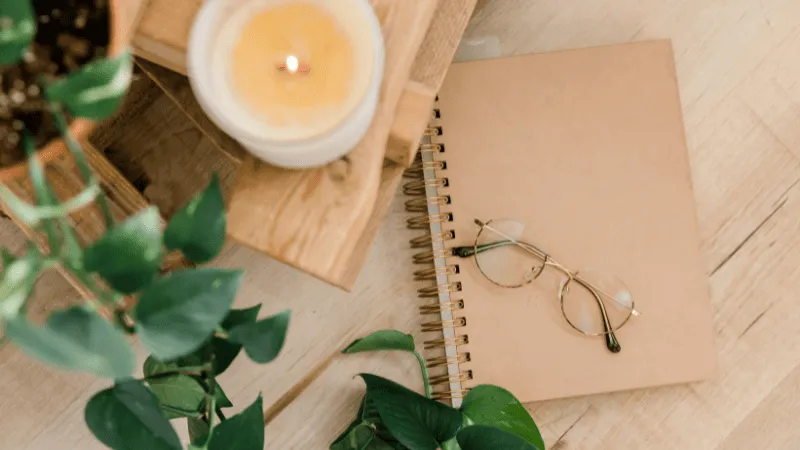 A candle, glasses, and a notebook are on the table.